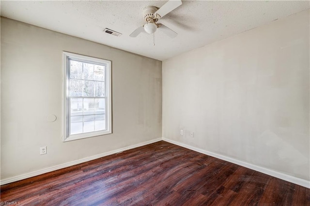 empty room featuring ceiling fan, dark wood-type flooring, and a textured ceiling