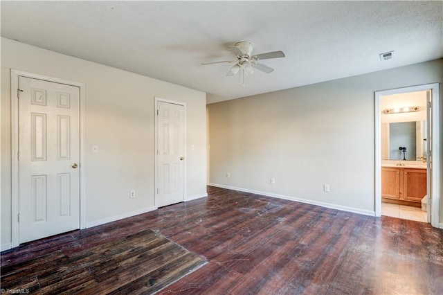 unfurnished bedroom featuring ceiling fan, dark wood-type flooring, and ensuite bath