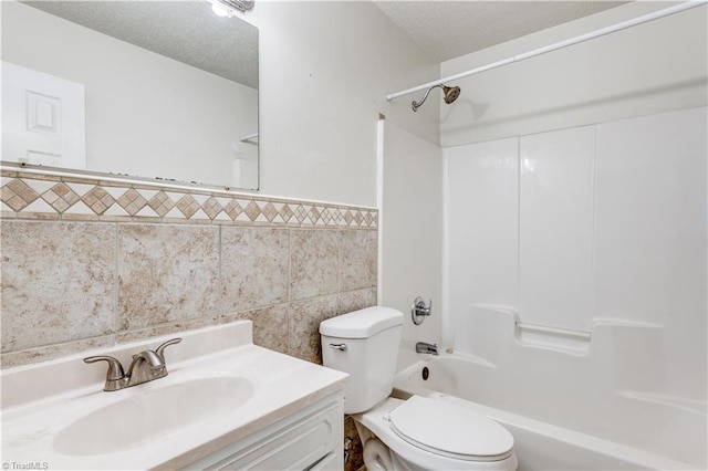 full bathroom featuring toilet, a textured ceiling, tile walls, shower / tub combination, and vanity