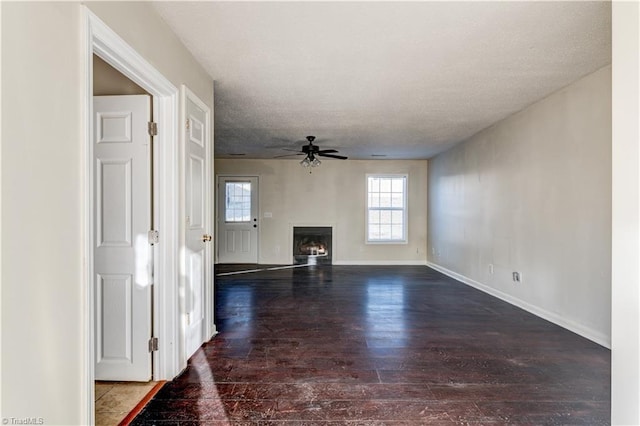 unfurnished living room with ceiling fan, dark wood-type flooring, and a textured ceiling