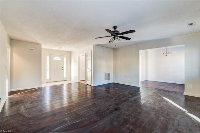 unfurnished living room featuring ceiling fan with notable chandelier, a textured ceiling, and dark hardwood / wood-style floors