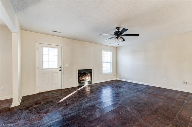 unfurnished living room with ceiling fan, a textured ceiling, and a wealth of natural light