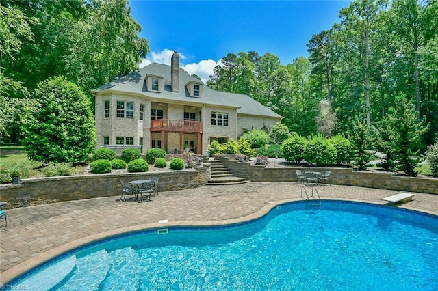 view of swimming pool with a patio and a diving board