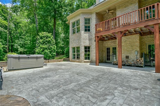 view of patio featuring ceiling fan, a hot tub, and a deck