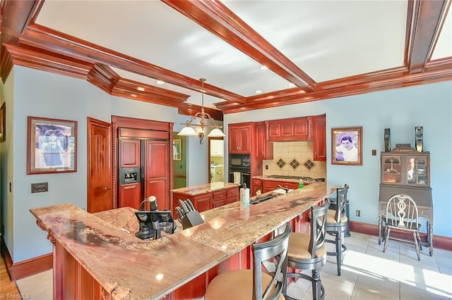 kitchen with built in appliances, decorative light fixtures, a center island, and beam ceiling