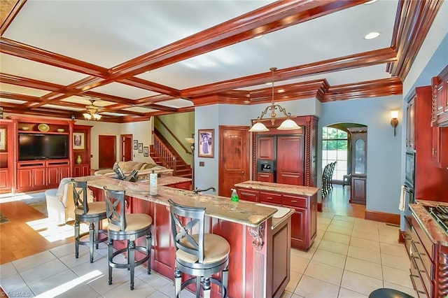 kitchen featuring hanging light fixtures, a kitchen bar, a kitchen island, light tile patterned flooring, and ceiling fan