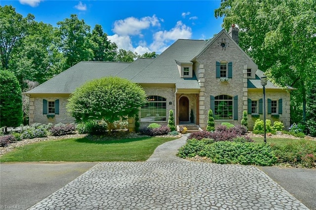 french country inspired facade with a front yard