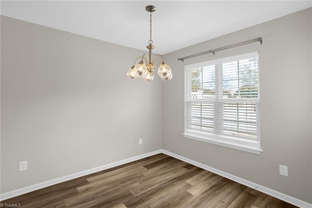 empty room featuring a chandelier and hardwood / wood-style floors