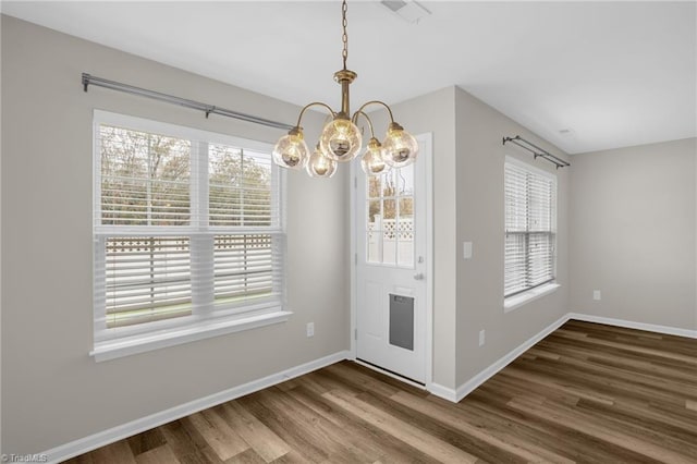 unfurnished dining area featuring a notable chandelier and hardwood / wood-style flooring