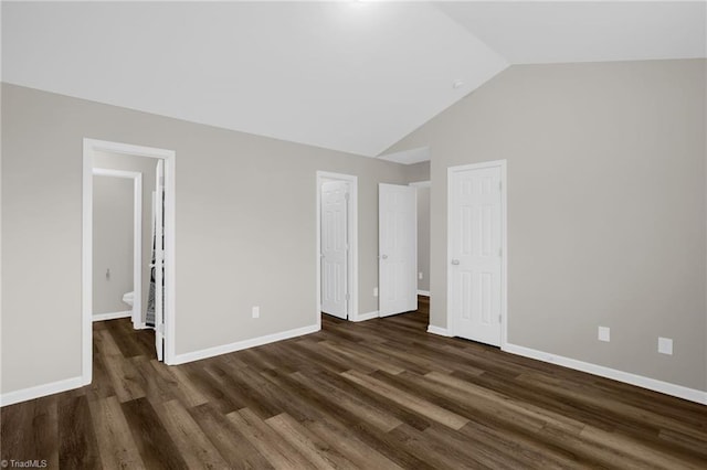 unfurnished bedroom featuring ensuite bathroom, dark hardwood / wood-style flooring, and vaulted ceiling