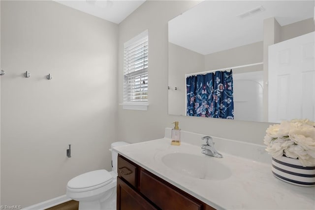 bathroom with walk in shower, vanity, and toilet