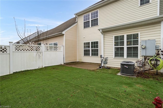 rear view of house with cooling unit, a yard, and a patio area