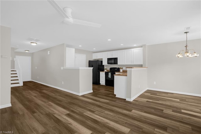 kitchen featuring dark wood-type flooring, black appliances, hanging light fixtures, kitchen peninsula, and white cabinets