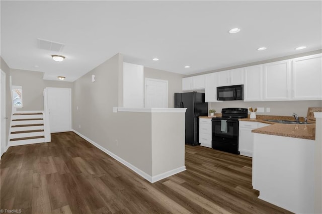 kitchen with dark hardwood / wood-style floors, white cabinetry, sink, light stone counters, and black appliances