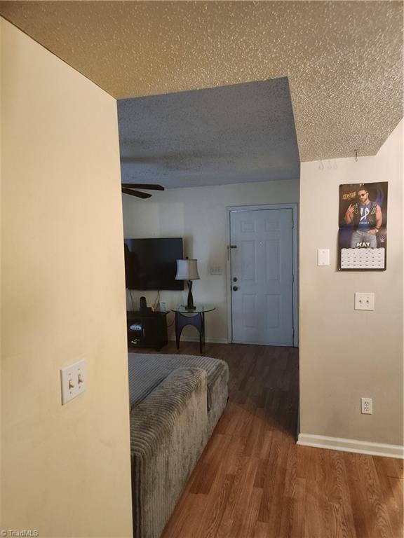 5517 Hornaday Rd Unit D, Greensboro, NC 27409 - hallway featuring wood finished floors, a textured ceiling, and baseboards