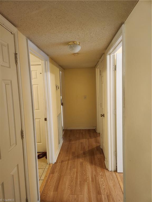 5517 Hornaday Rd Unit D, Greensboro, NC 27409 - hall with light wood-type flooring and a textured ceiling