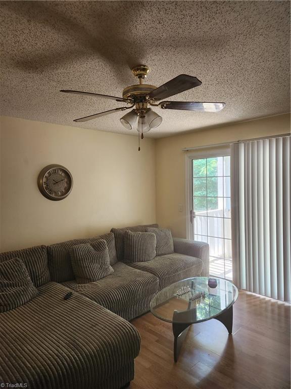 5517 Hornaday Rd Unit D, Greensboro, NC 27409 - living room with wood finished floors, ceiling fan, and a textured ceiling