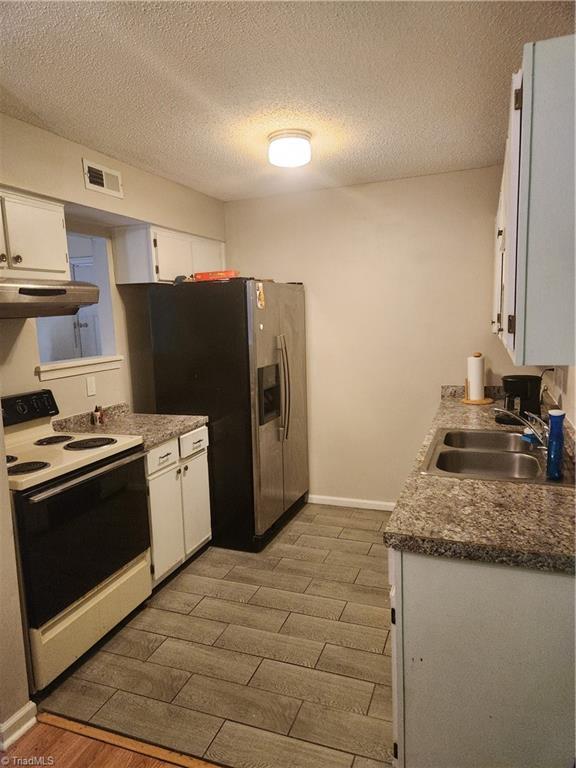 5517 Hornaday Rd Unit D, Greensboro, NC 27409 - kitchen with white range with electric stovetop, under cabinet range hood, a sink, wood finished floors, and stainless steel fridge with ice dispenser