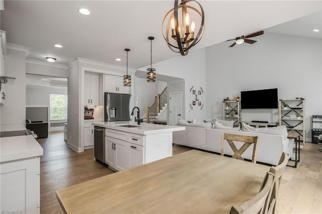 kitchen with stainless steel appliances, white cabinets, ceiling fan with notable chandelier, a sink, and open floor plan