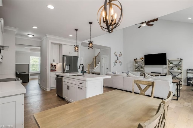 kitchen featuring ceiling fan with notable chandelier, white cabinets, a kitchen island with sink, and hanging light fixtures