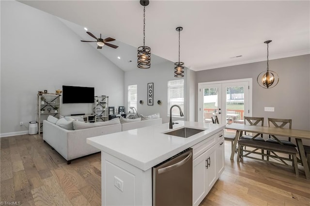 kitchen featuring light wood-style flooring, a sink, dishwasher, french doors, and hanging light fixtures