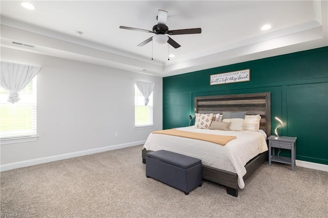 carpeted bedroom featuring multiple windows, a tray ceiling, and ceiling fan