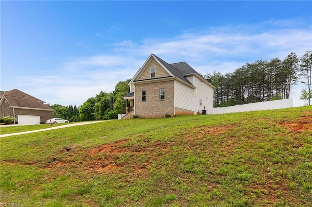 view of property exterior with a yard, a garage, and brick siding