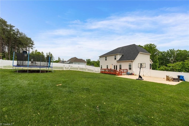 view of yard with a deck, a trampoline, a patio, and a fenced backyard