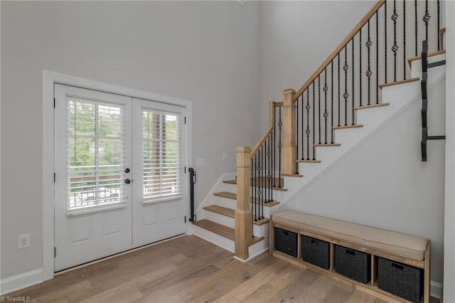 entryway with a high ceiling, light hardwood / wood-style floors, and french doors