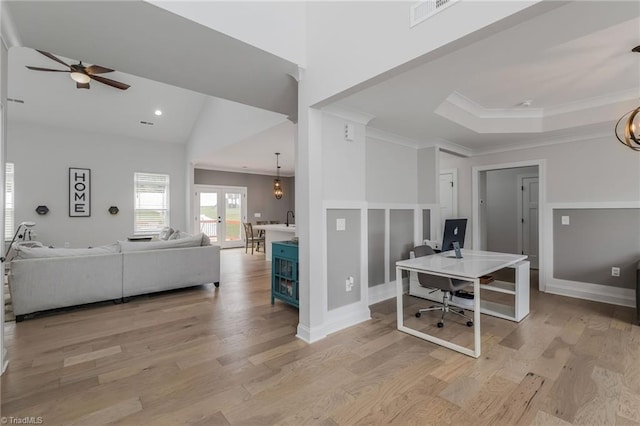 interior space with light wood-style floors, ceiling fan with notable chandelier, visible vents, crown molding, and a tray ceiling