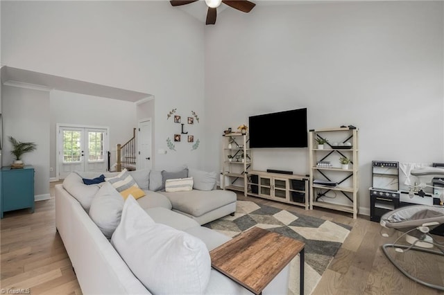 living room with french doors, wood finished floors, a ceiling fan, high vaulted ceiling, and stairs