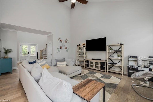 living room with ceiling fan, hardwood / wood-style flooring, and a towering ceiling