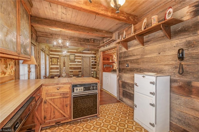 kitchen with hanging light fixtures, wooden walls, beam ceiling, washer and clothes dryer, and butcher block counters