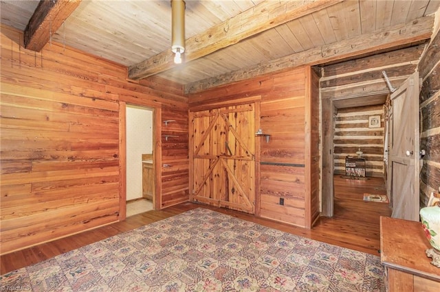 unfurnished bedroom with hardwood / wood-style flooring, beam ceiling, and wooden walls