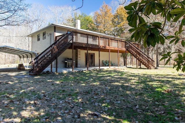 back of property featuring a chimney, stairway, a deck, a yard, and a carport