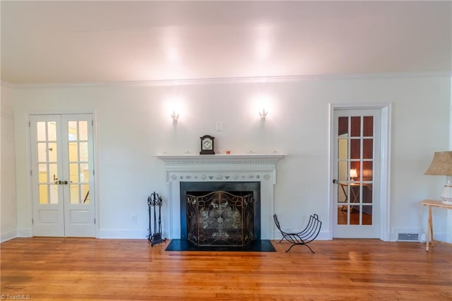 unfurnished living room with french doors, ornamental molding, and wood-type flooring