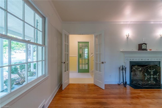 living room featuring french doors, crown molding, and light hardwood / wood-style flooring