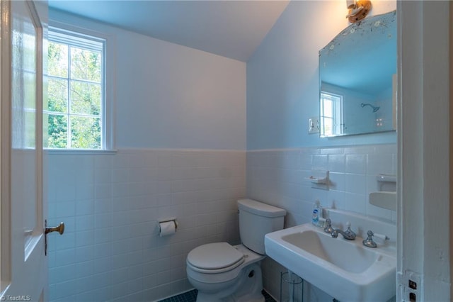 bathroom with toilet, sink, and tile walls