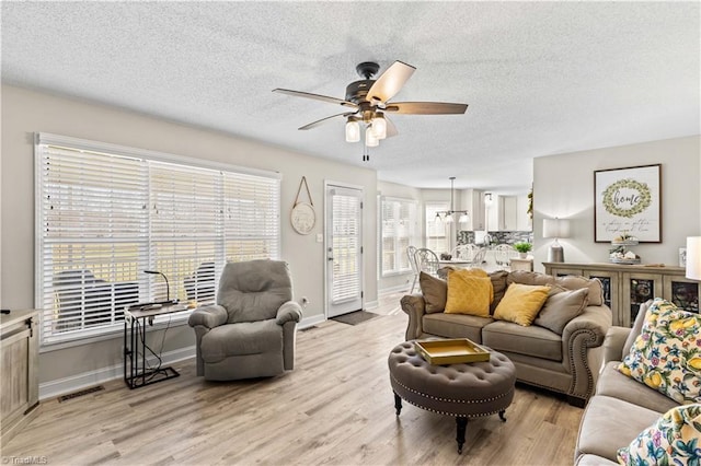 living room with a textured ceiling, light wood-type flooring, plenty of natural light, and ceiling fan