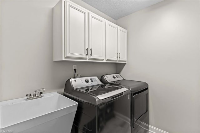 washroom with washer and dryer, a textured ceiling, cabinets, and sink