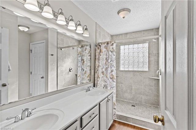 bathroom featuring tiled shower, hardwood / wood-style floors, vanity, and a textured ceiling