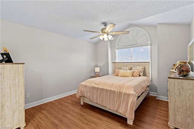 bedroom featuring a textured ceiling, ceiling fan, wood-type flooring, and lofted ceiling