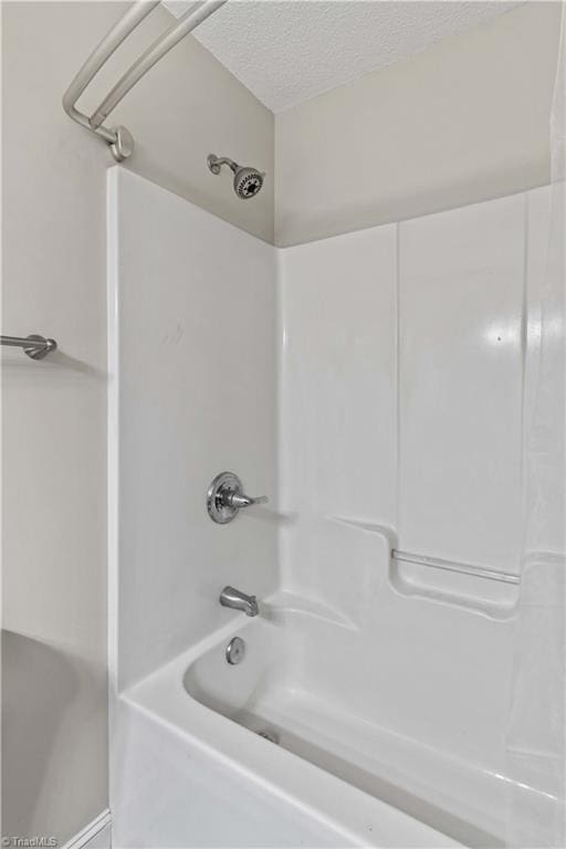 bathroom with a textured ceiling and shower / bathtub combination