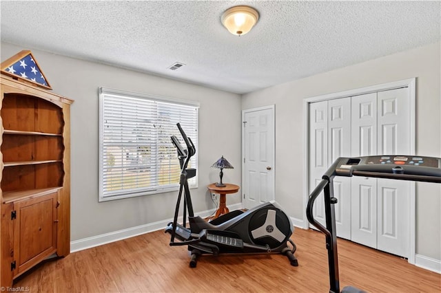 exercise room featuring wood-type flooring and a textured ceiling