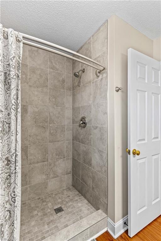 bathroom featuring hardwood / wood-style flooring, curtained shower, and a textured ceiling