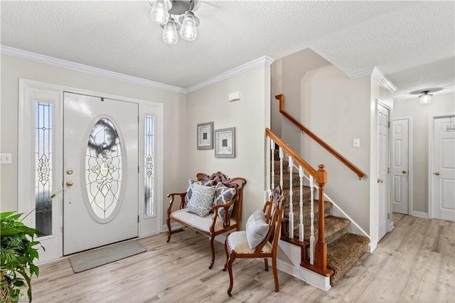 foyer entrance with a textured ceiling, light hardwood / wood-style flooring, and crown molding