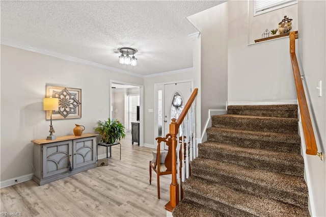 entrance foyer featuring light hardwood / wood-style floors, ornamental molding, and a textured ceiling