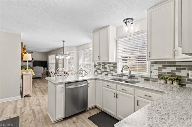 kitchen featuring light stone countertops, sink, hanging light fixtures, stainless steel dishwasher, and white cabinets