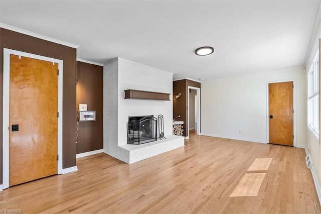 unfurnished living room with light wood-style flooring, a fireplace, baseboards, and ornamental molding