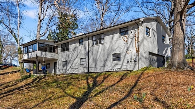 view of side of property featuring a garage, brick siding, and a sunroom